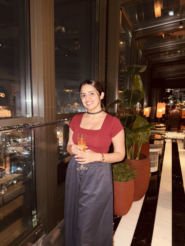 Girl with champagne in hand at a rooftop restaurant.